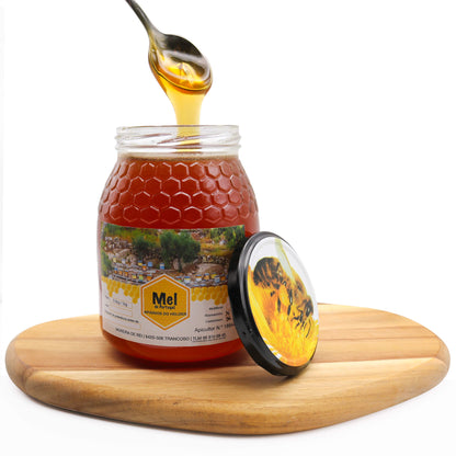 jar of raw honey on wooden board with spoon full of honey dripping into jar