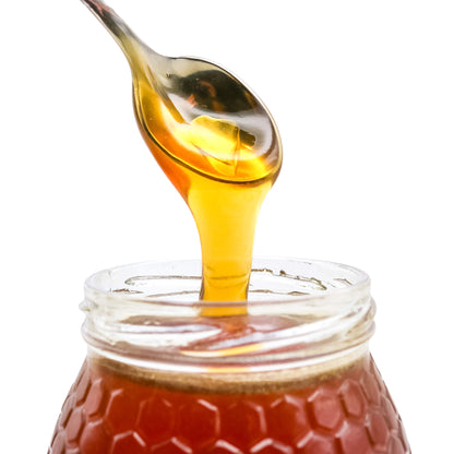 honey dripping from spoon into jar