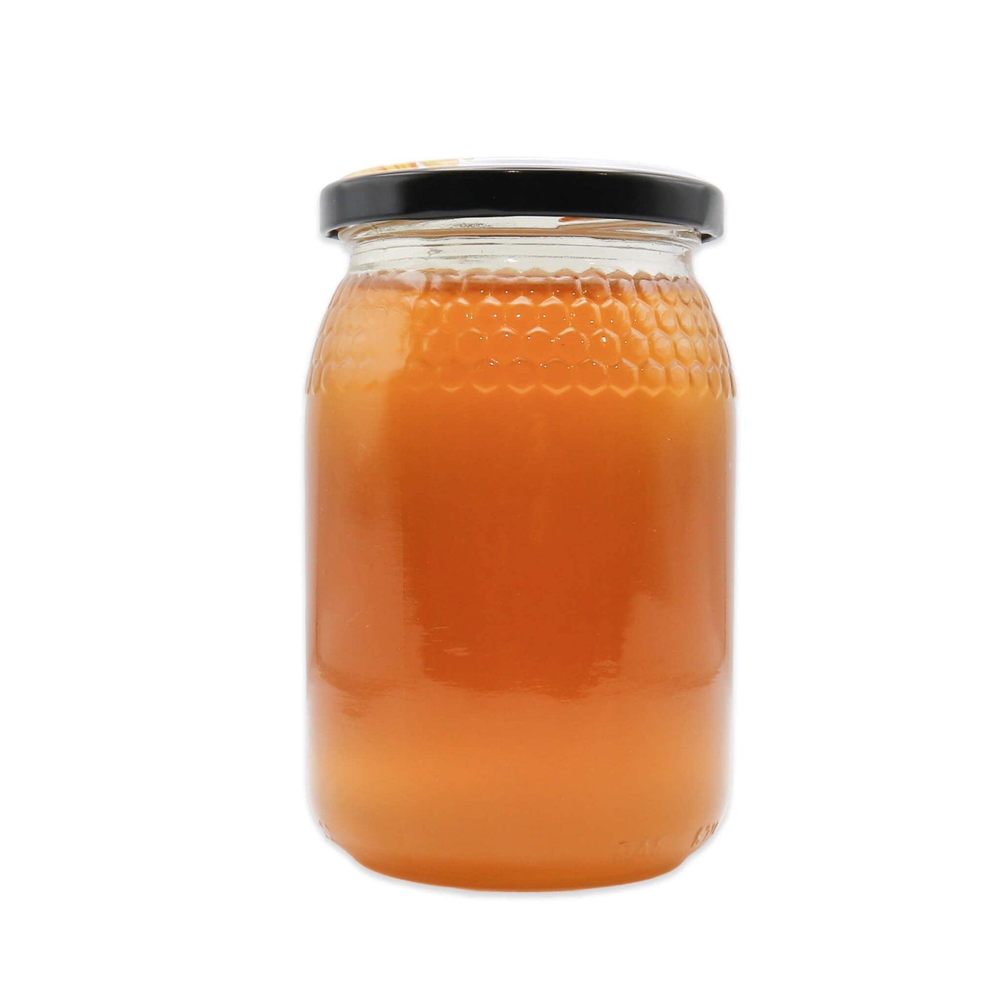 Jar of honey with a black lid on a white background